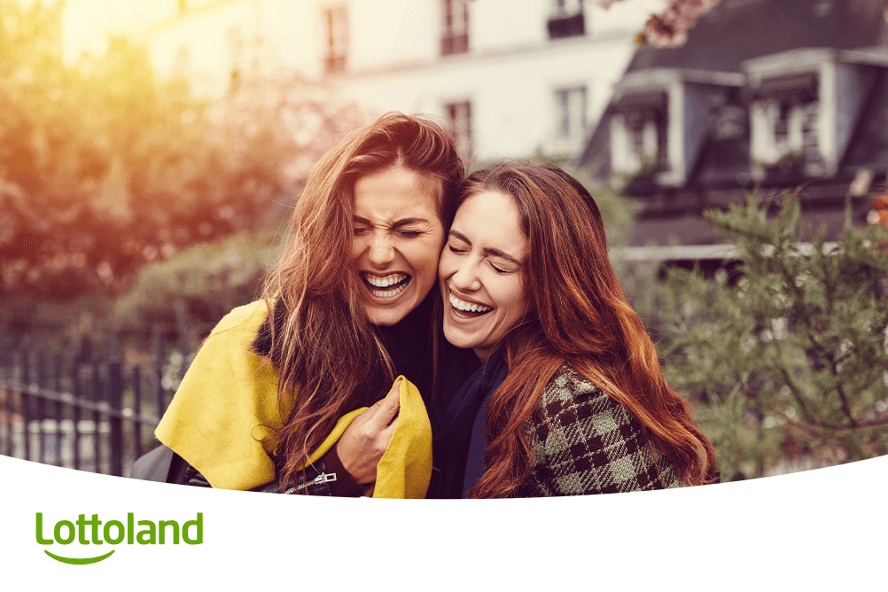 Zwei fröhliche Frauen lachen ausgelassen im Freien – sie feiern ihr Lotto-Glück laut Horoskop und den Daten der Lottoland-Sternzeichenanalyse